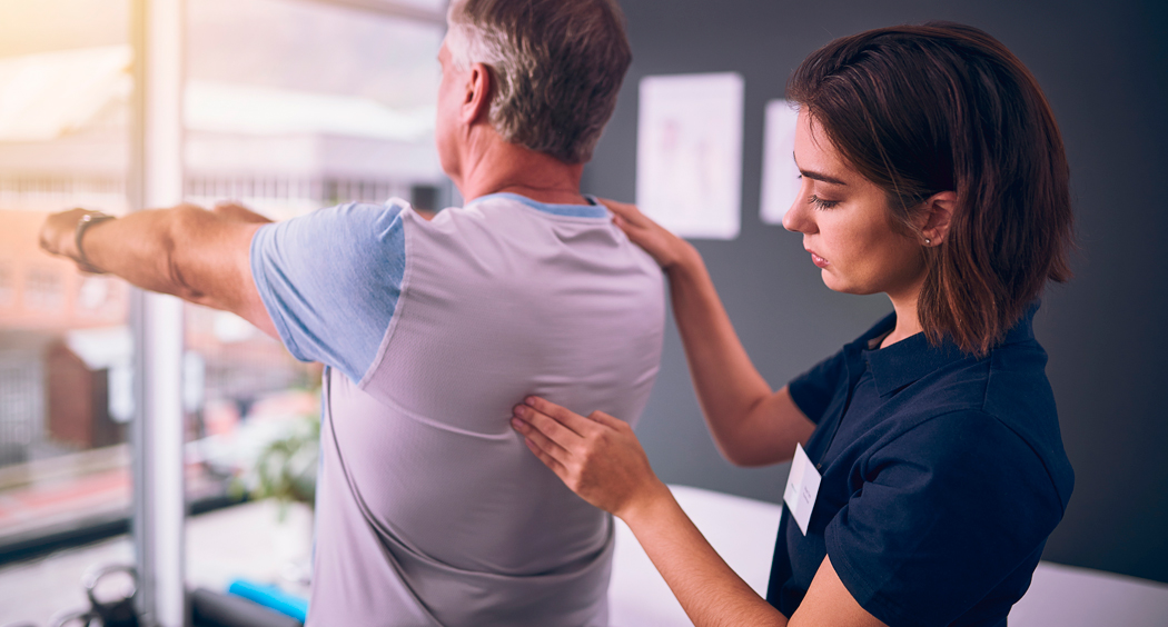 Fisioterapeuta evaluando y corrigiendo el movimiento del hombro de un paciente durante una sesión de rehabilitación personalizada en el Centro Médico de Rehabilitación Majadahonda.