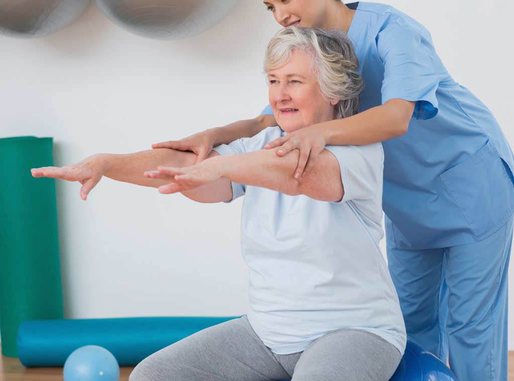 Fisioterapeuta ayudando a una paciente mayor a realizar ejercicios de movilidad y equilibrio durante una sesión de fisioterapia especializada en mayores en el Centro Médico de Rehabilitación Majadahonda.