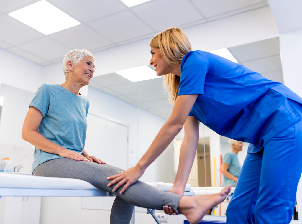 Fisioterapeuta realizando valoración y movilización de la pierna a una paciente mayor durante una sesión de fisioterapia especializada en mayores en el Centro Médico de Rehabilitación Majadahonda.